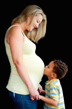 Young child kisses his mom's pregnant stomach