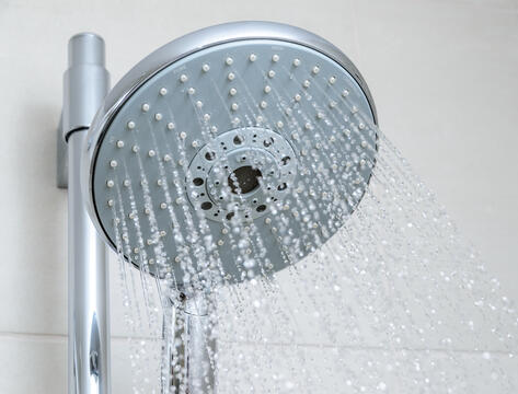 Close up of the front of a running shower head