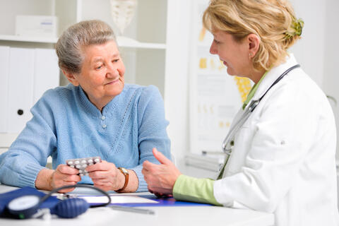 Physician talks to an elderly person about medications with blood pressure meter in the front