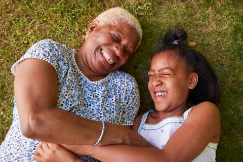 Senior and young girl lying on the grass laughing together