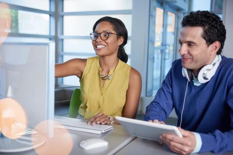 Two coworkers with a tablet and a desktop computer