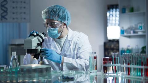 Adult in a laboratory adjusting a microscope