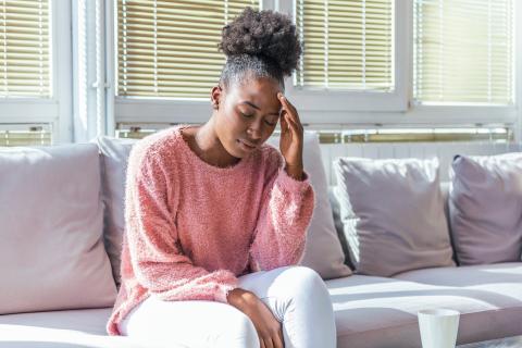 Person with headache sitting on a sofa