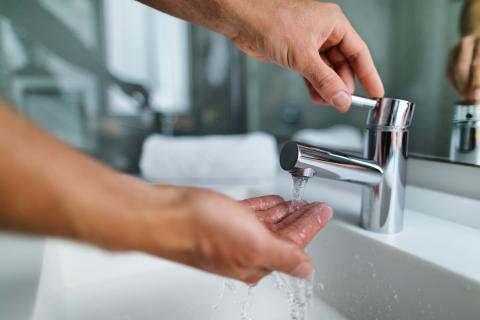 Close up of adult washing hands at sink