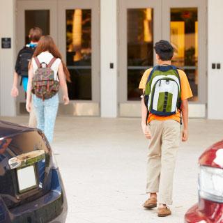 Kids walking into school wearing backpacks