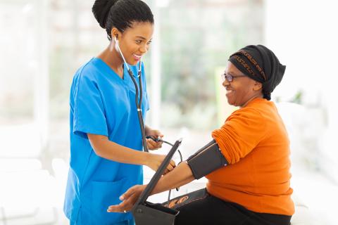 A smiling nurse check a patient's blood pressure.