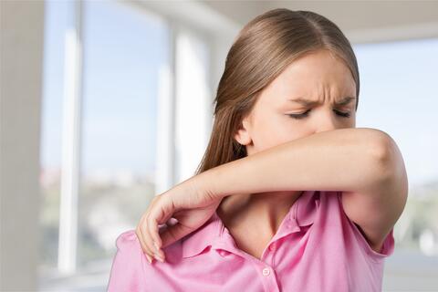 An adult coughing into her elbow.