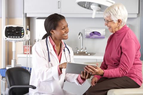 A doctor uses a tablet with a patient.