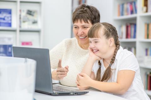 Older adult and teen laughing while watching a laptop