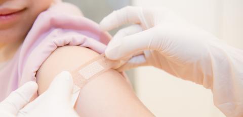 Applying a bandage to an arm after an injection.