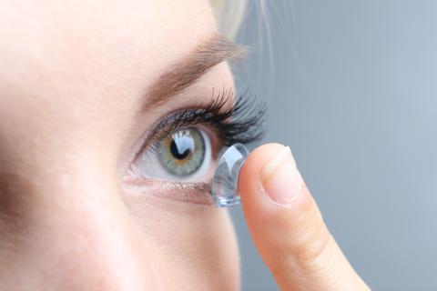 Close up of an adult inserting contact into eye.