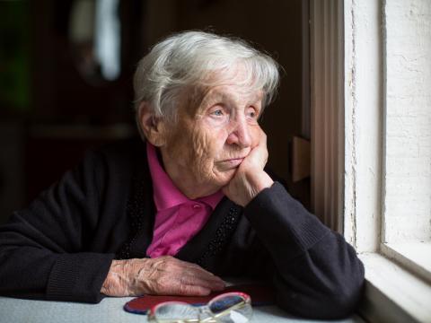 Sad older adult looking out a window
