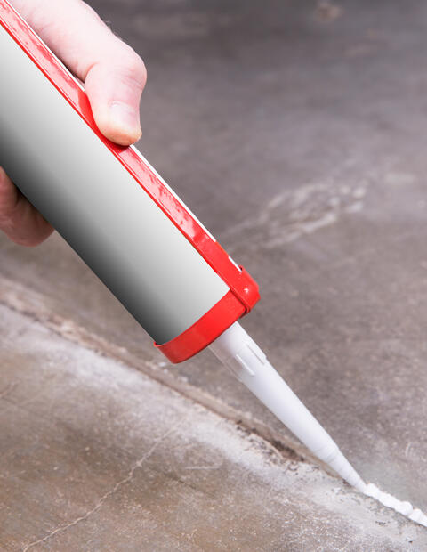 Person using a tube of sealant to seal cracks