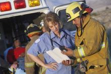 A firefighter discussing with an EMT by the ambulance.