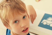 Child next to artwork of a car on a desk.