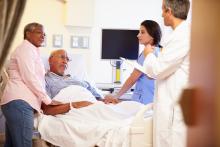 Two doctors treat an elderly in the hospital who is accompanied by a partner