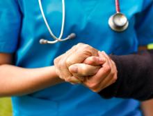 Healthcare provider's hand holding a patient's hand