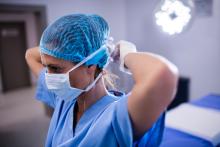 Nurse tying on her surgical mask