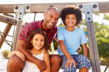 An happy adult with two children sitting on a playground ladder.