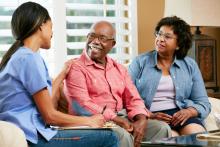 A caretaker talks with a couple during in-home visit