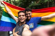 Two adults taking a selfie with a rainbow flag