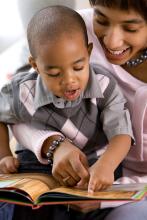 An adult reads to a toddler.