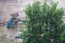 Pouring rain flooding a playground with a tree