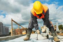 Construction worker with hard hat, uses a grinder on a site