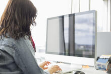 An adult at a desk working on a computer.