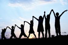 A silhouette of children standing and holding hands in the sky