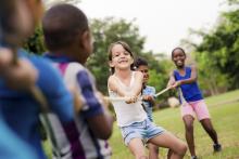 Happy children playing tug of war outside.