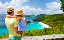 Adult and child enjoying a tropical beach view from a parapet