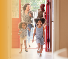 Family of four entering a home