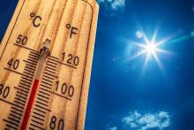 Thermometer under blue sky and hot sun with temperature over 100 F
