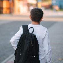 Child with backpack walking down street