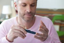 An adult performs an insulin test on his finger