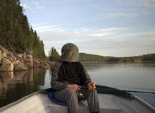 An adult was wearing mosquito net over his face while fishing.