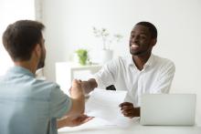 Smiling two adults shaking hands across a desk