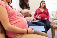 Three pregnant people sit in a circle at a prenatal class