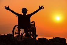 Silhouette of an adult in a wheelchair at sunset