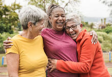 Three multi-generational adults embrace outside