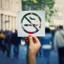 Hand holding a paper no smoking sign