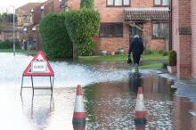 A flooded street with a sign and two cones.