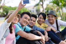 Teens taking a "selfie" picture together outside
