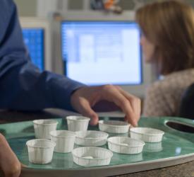 Tray of pills in white paper cups ready for distribution at a facility