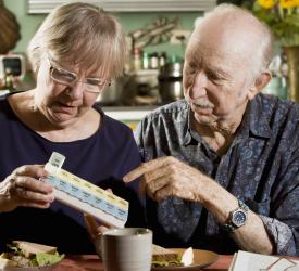 Elder couple sort their medications into a daily medicine organizer at home
