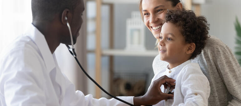 Toddler sitting on adult lap while doctor listens to his heart Toddler sitting on adult lap while doctor listens to his heart